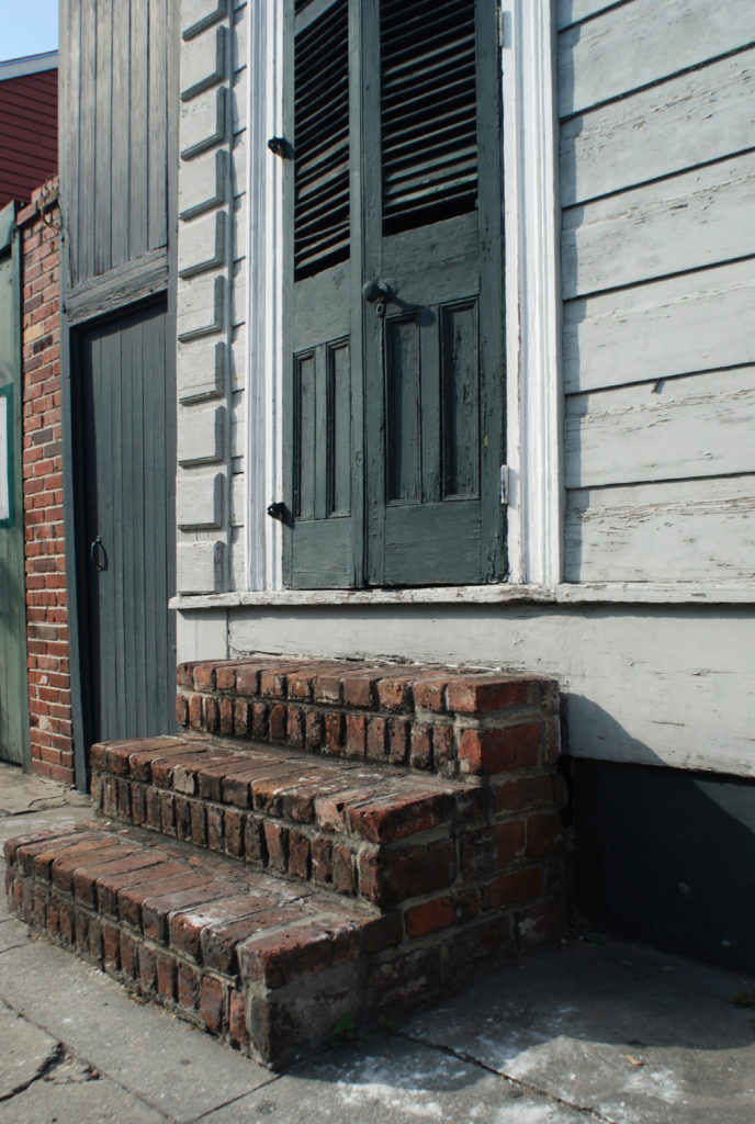 brick stoop of shotgun house with green shutters