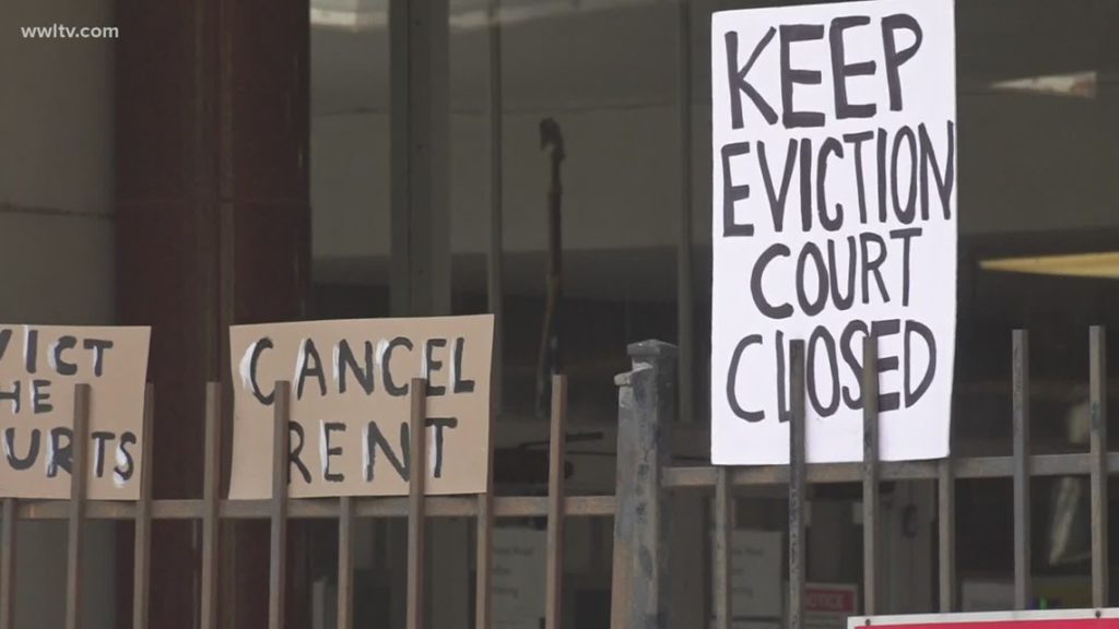 fence with handwritten signs that say "cancel rent" and "keep eviction court closed"