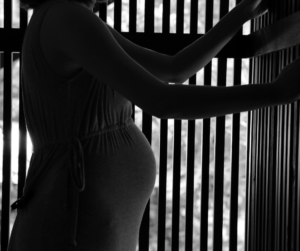black and white photo of silhouette of pregnant mother's belly