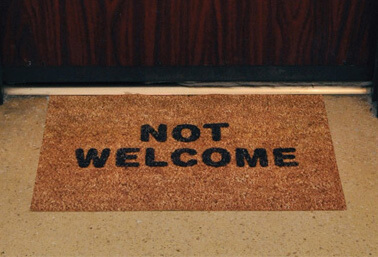 welcome mat by door that has "not welcome" printed on it