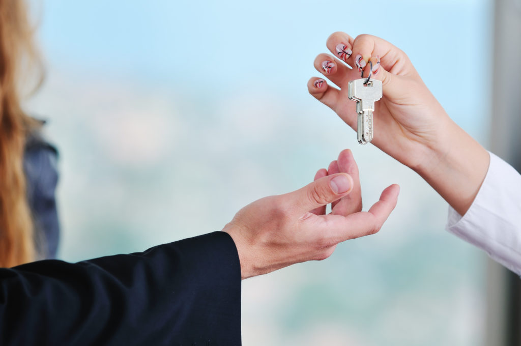 Manos de dos personas con las llaves de la casa que representa la compra y venta de un apartamento nuevo y el concepto de bienes inmuebles