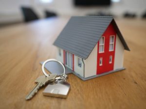 key resting beside tiny model of a house on wooden table