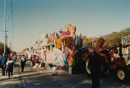 mardi gras float with people walking beside it