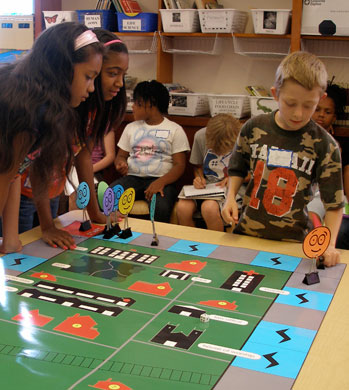 two girls and a boy around a table playing a board game