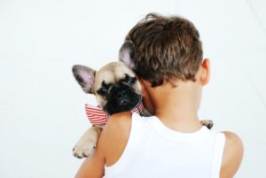a boy holding a puppy with a bow around its neck