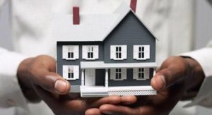 hands of an african american person holding model of grey colored house