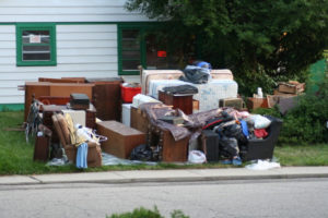 an eviction showing furniture and household items piled on the sidewalk outside of a home